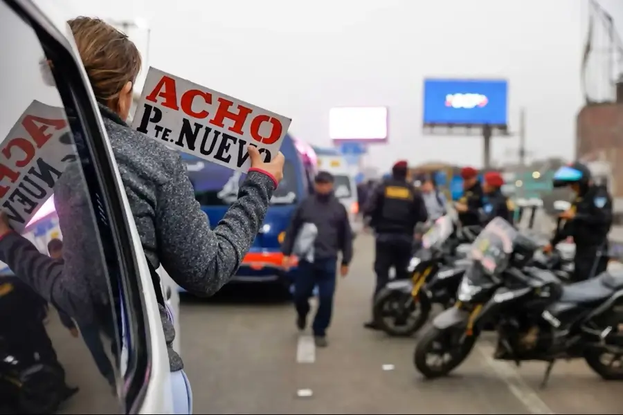 un letrero que indica la ruta del transporte publico sostenido por una mujer