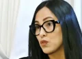 Mujer de cabello negro y gafas oscuras observando un documento en un ambiente interior