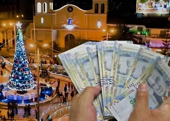 billete peruano en una mano, de fondo un arbol navideño