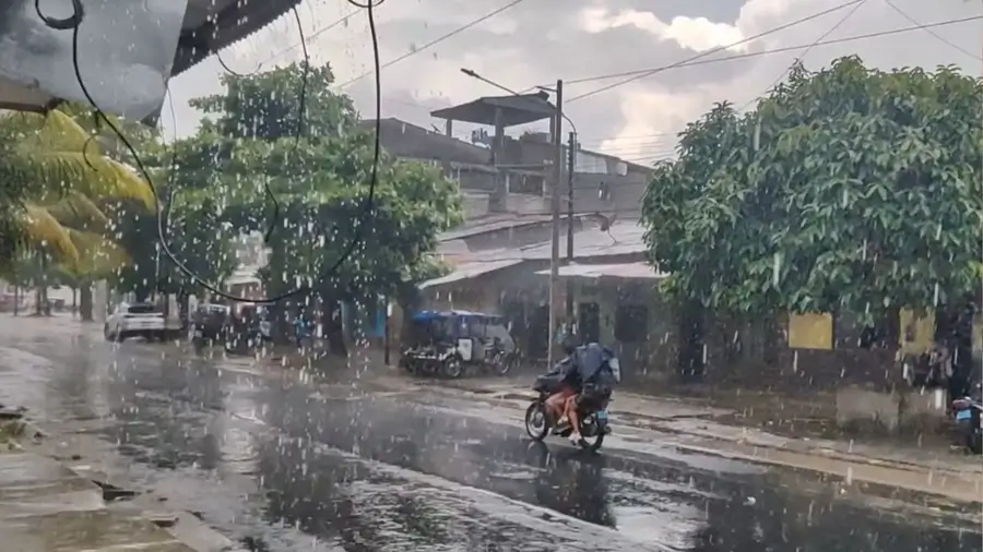 Fuerte lluvia cae sobre una calle urbana del Perú; motociclista circula bajo la lluvia y el pavimento luce mojado por las precipitaciones