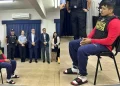 Erick Moreno, alias “el Monstruo”, permanece sentado y esposado durante una presentación oficial de Interpol, con agentes y autoridades detrás, previo a su proceso de extradición al Perú.