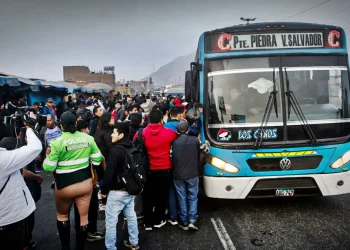 Pasajeros y transportistas rodean un bus de transporte público en Lima durante una protesta por paro del sector.