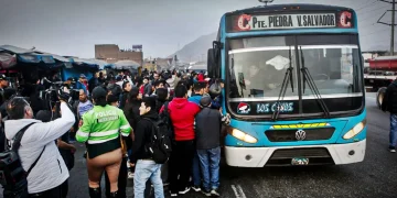 Pasajeros y transportistas rodean un bus de transporte público en Lima durante una protesta por paro del sector.