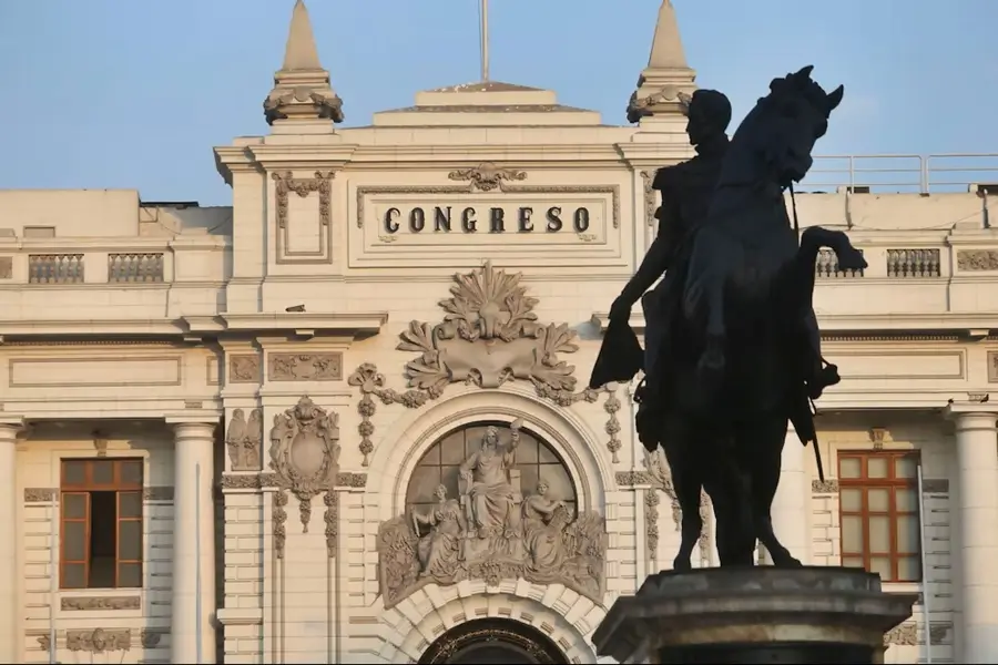 Estatua ecuestre en primer plano frente a la fachada del Congreso de la República del Perú, edificio histórico de estilo republicano.