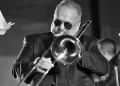 Willie Colón tocando trombón en concierto en blanco y negro con paloma blanca
