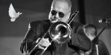 Willie Colón tocando trombón en concierto en blanco y negro con paloma blanca