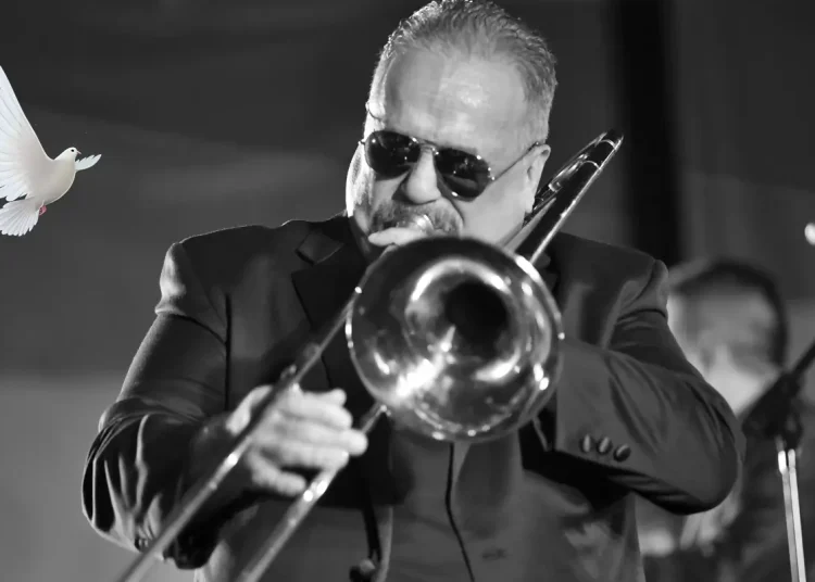 Willie Colón tocando trombón en concierto en blanco y negro con paloma blanca