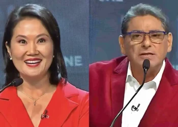 Keiko Fujimori y Carlos Álvarez durante un debate o programa televisivo, ambos usando vestimenta roja y micrófonos de solapa sobre un fondo con pantallas digitales.