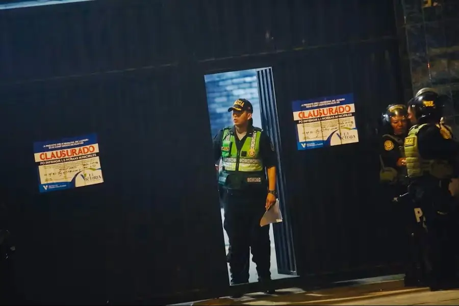 Un efectivo de la Policía Nacional sale por una pequeña puerta del estadio de Matute, flanqueada por dos carteles azules de "Clausurado" de la Municipalidad de La Victoria.