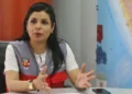 Funcionaria peruana sentada en una mesa de oficina, gesticulando mientras habla, con un mapa del Perú al fondo.