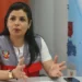 Funcionaria peruana sentada en una mesa de oficina, gesticulando mientras habla, con un mapa del Perú al fondo.