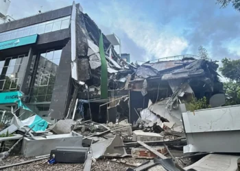 Edificio de Bancaribe colapsado y en ruinas tras un terremoto en Venezuela, mostrando daños estructurales masivos y escombros.