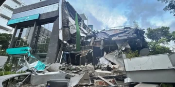 Edificio de Bancaribe colapsado y en ruinas tras un terremoto en Venezuela, mostrando daños estructurales masivos y escombros.