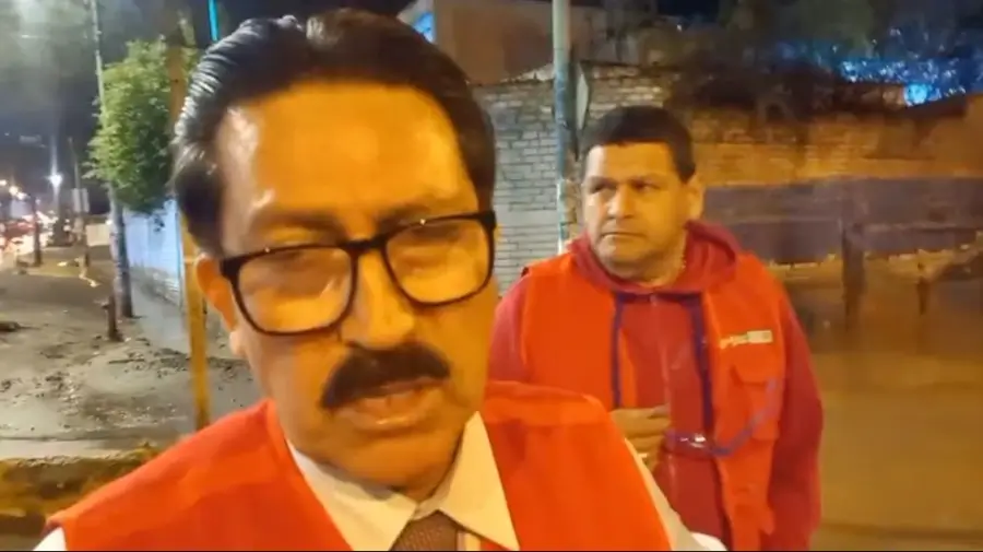 Cobertura de prensa sobre los daños en Lima tras intensas lluvias con funcionario de chaleco rojo en primer plano