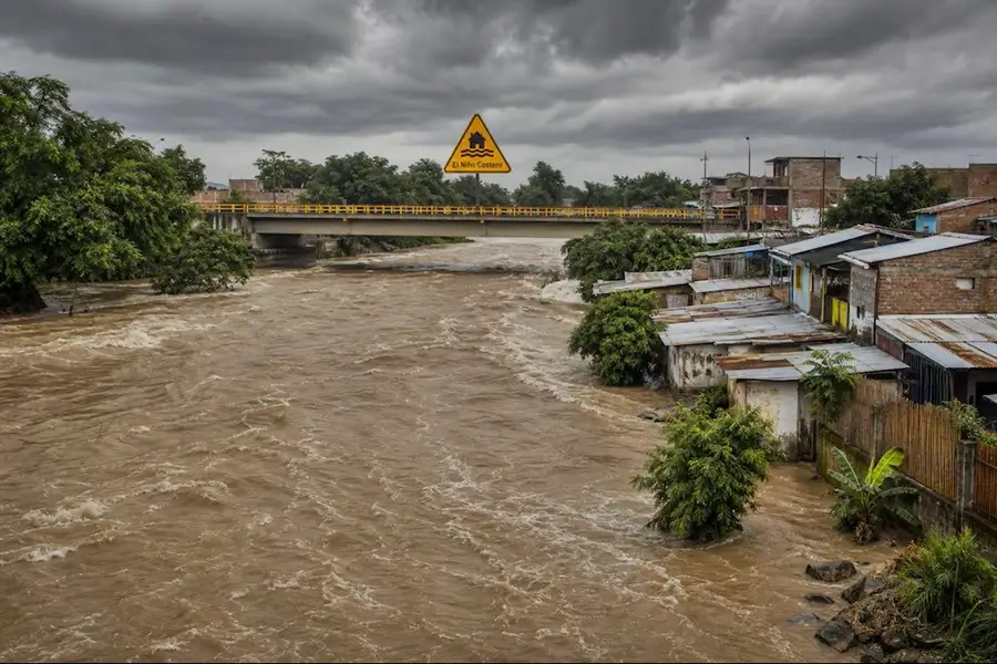 Caudal de río crecido y casas afectadas durante las emergencias por el Fenómeno El Niño Costero en Perú