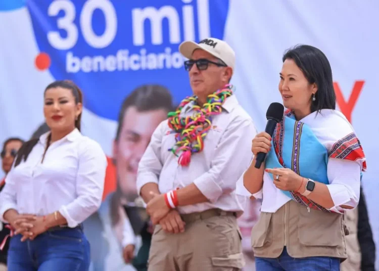 Keiko Fujimori habla por un micrófono sosteniendo una chalina tradicional durante un mitin político.