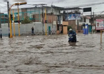 Motociclista avanza por una calle completamente inundada tras intensas lluvias en el norte del Perú.