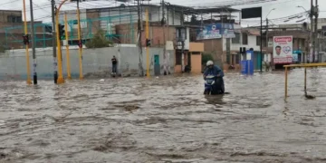 Motociclista avanza por una calle completamente inundada tras intensas lluvias en el norte del Perú.